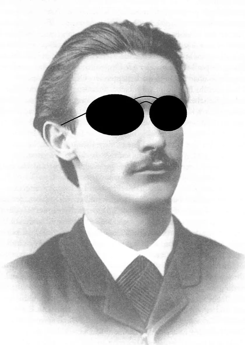 Portrait en noir et blanc d'un homme avec des lunettes noires, coiffé de cheveux bruns.