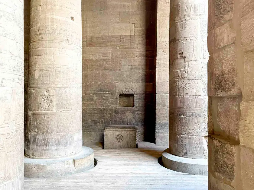 Intérieur d'un temple égyptien avec des colonnes sculptées et un autel en pierre.