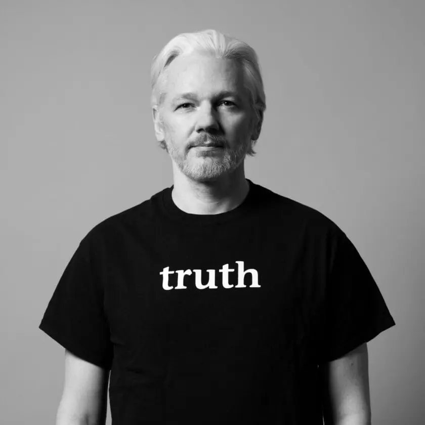 Homme aux cheveux blancs portant un t-shirt noir avec le mot 'truth' écrit en blanc.