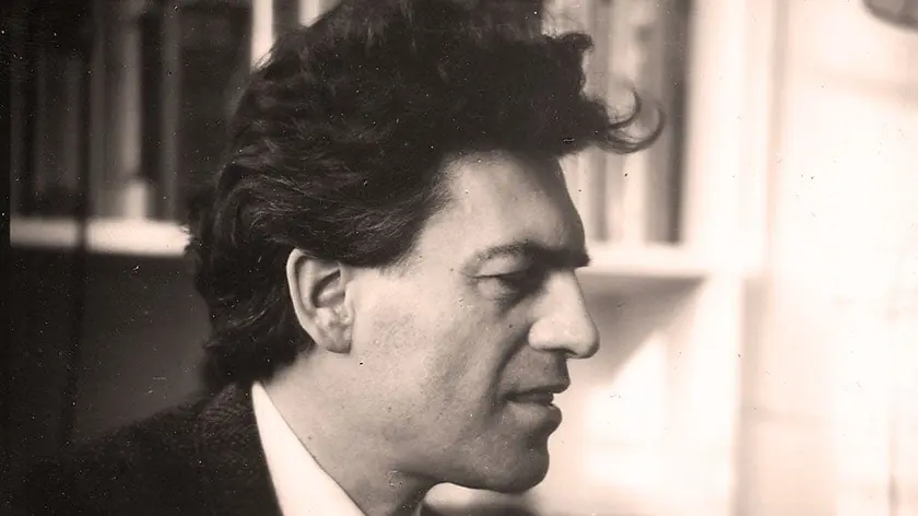 Profil d'un homme avec des cheveux bouclés, dans un cadre intérieur flou.