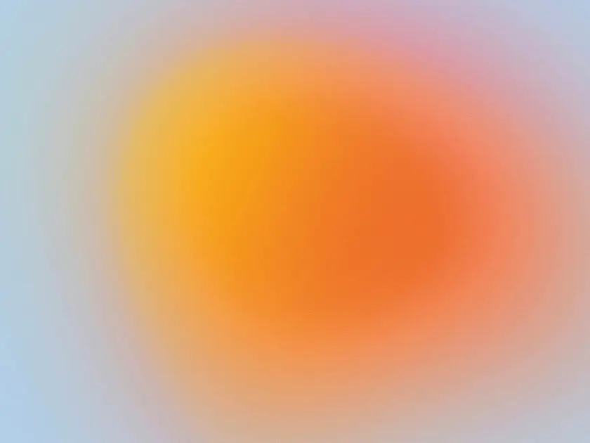 Un flou de couleurs chaudes, principalement orange et jaune, sur un fond pastel.