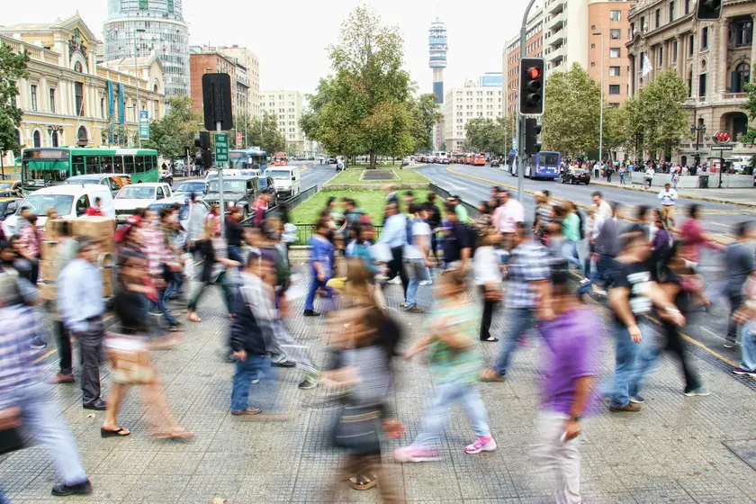 Une rue animée avec des piétons en mouvement flou, entourée de bâtiments urbains.