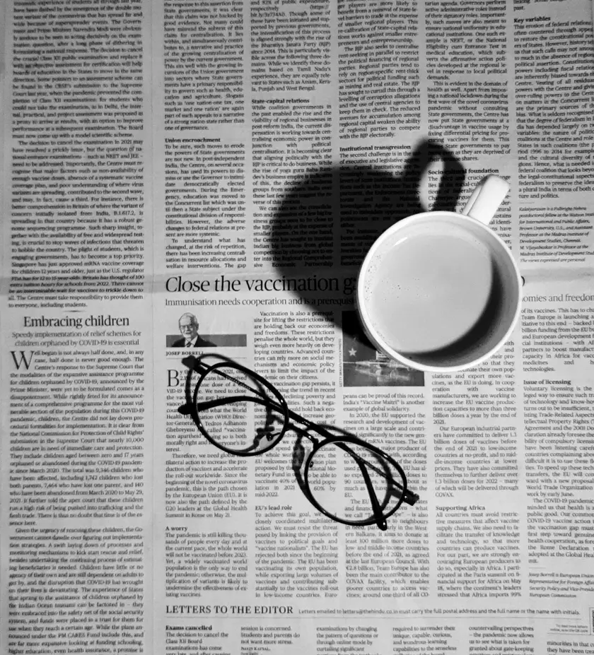 Une tasse de café posée sur un journal, avec des lunettes à côté.