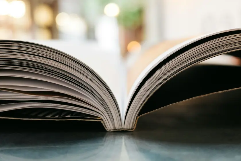 Un livre ouvert posé sur une surface, avec des pages visibles et un flou en arrière-plan.