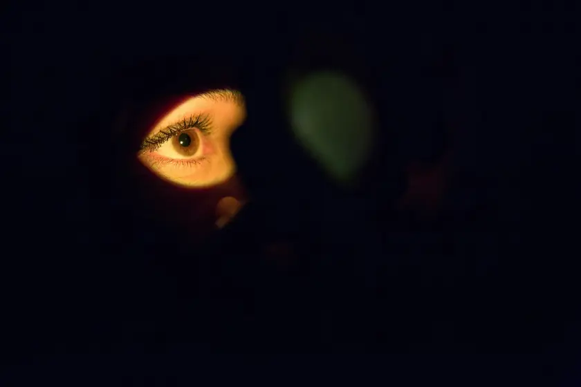 Un œil humain éclairé par une lumière douce, entouré d'obscurité.